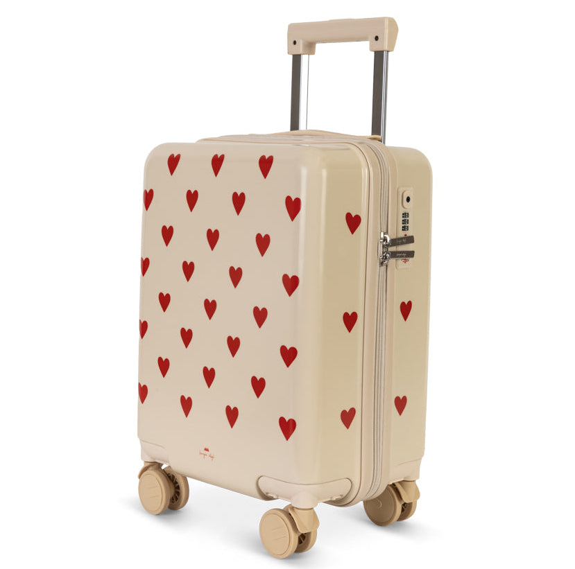 Off-white Kids’ Travel Suitcase by Konges Slojd patterned with small red hearts, featuring a retractable handle and a side TSA lock.