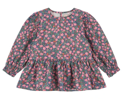 The Girls' Cianna Blouse by Konges Slojd is a long-sleeve woven cotton top for children, featuring a ruffled hem and a dark background with an all-over pink and purple floral print.