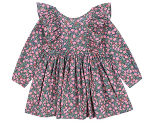 The Girls' Cianna Bow Dress by Konges Slojd is a long-sleeve organic cotton dress with a pink floral print on a dark background, featuring frill sleeves, ruffled shoulders, and a gathered waist.