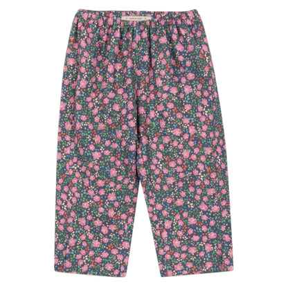 The Konges Slojd Girls' Cianna Pants are loose-fitting, soft pants with an elastic waist, showcasing a dark background and an all-over pink and green floral print.