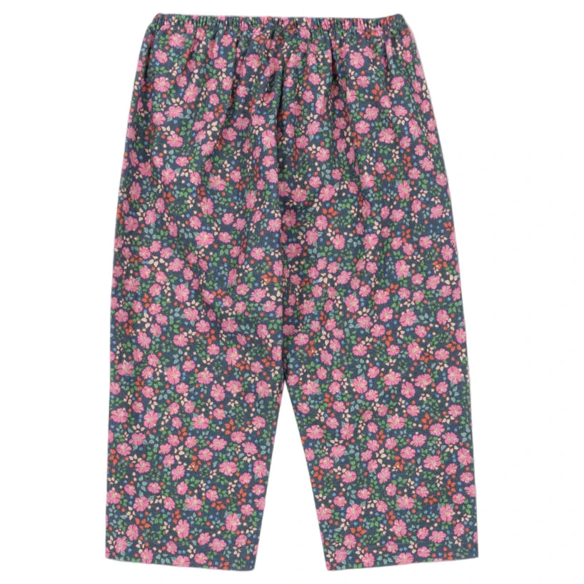 The Girls' Cianna Pants by Konges Slojd are loose-fitting and soft, with a comfy elastic waist and a dark base adorned with an all-over pink and purple floral print.