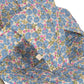 Close-up of a washable cotton cushion with blue, pink, and green floral pattern on white, placed on a metal-framed Konges Slojd Doll Bouncer—ideal for your child's playtime.