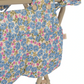 Close-up of the Konges Slojd Doll Changing Table featuring a padded cover with a blue, pink, and green floral pattern on a beige metal frame.