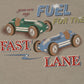 The Konges Slojd Baby Boys' and Boys' Drey Tee features two cartoon race cars, green and blue, racing on beige with "you are my FUEL FOR THE FAST LANE"—a playful, organic cotton shirt perfect for kids.