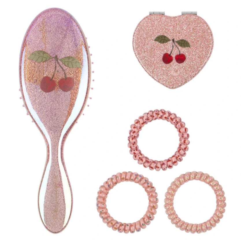 The Get Ready With Me Set by Konges Slojd includes a pink cherry hair brush, a heart-shaped hand mirror with cherries, and four pink spiral hair ties. Displayed on white, this set is ideal for your toiletry bag.