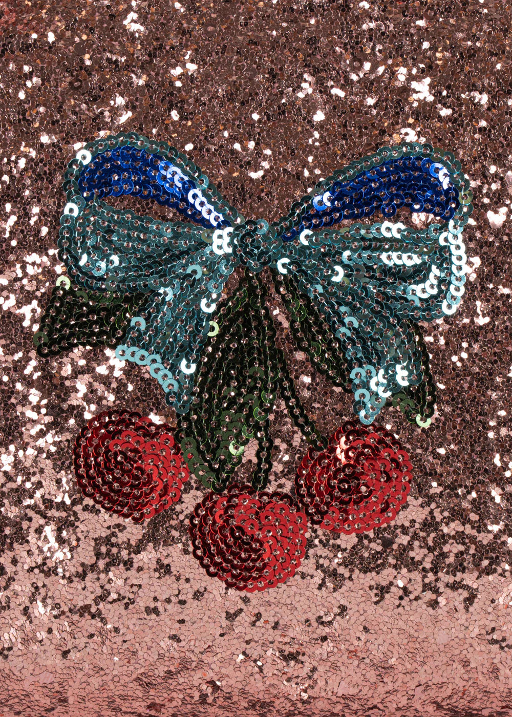 The Get Ready With Me Set by Konges Slojd features a sequin patch of a blue-green bow with red cherries on a pink background—perfect for adding vibrant flair to your toiletry bag or hand mirror.