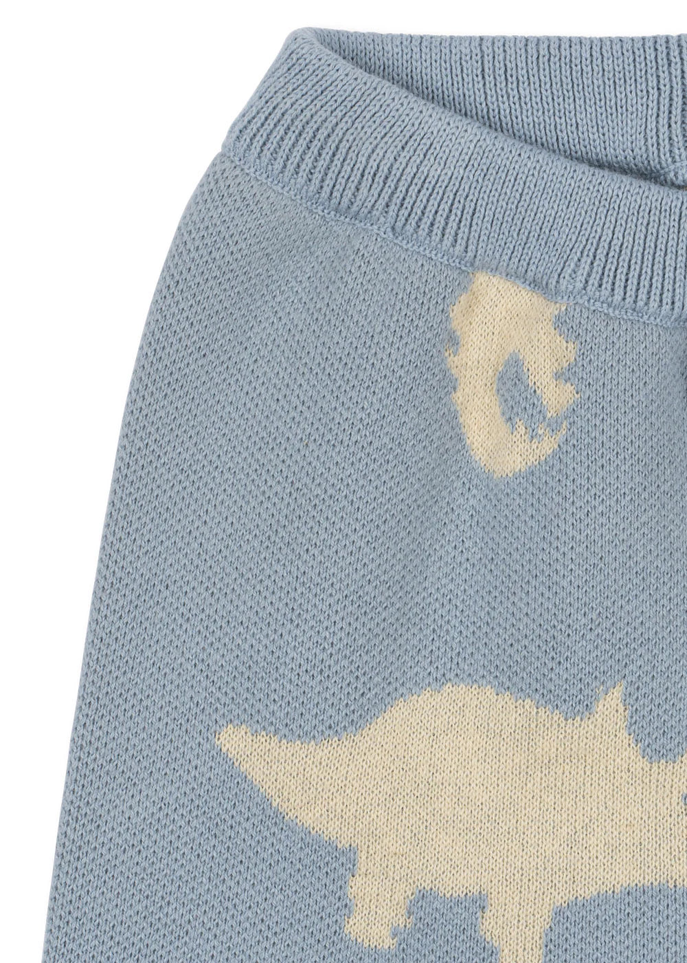 Close-up of Konges Slojd Baby Boys' and Boys' Lapis Knit Pants in light blue, featuring a cream dinosaur jacquard pattern and a ribbed, elastic waist.