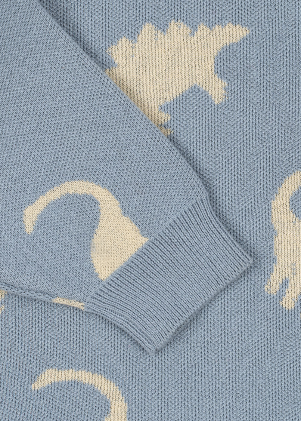The Konges Slojd Baby Boys' and Boys' Lapis Knit Sweater features a relaxed fit in blue with white dinosaur silhouettes, ribbed cuffs, and rib hems.