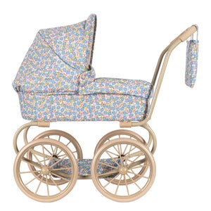 The Minnie Doll Pram by Konges Slojd features a floral fabric cover, beige metal frame, four large spoked wheels, and a matching bag—ideal for kids who love classic style.