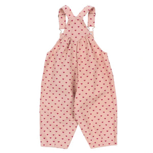 Konges Slojd Baby Girls' and Girls' Nola Sequin Overalls in light pink with overall-style straps, logo buttons, and small red heart pattern, shown on a white background.