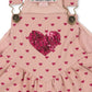 The Konges Slojd Baby Girls' and Girls' Nola Sequin Overalls feature a pink heart print, a sparkly sequin heart on the chest, adjustable brass buckle straps, and chic logo buttons for extra style.