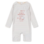 The Baby Boys’ Aster Onesie Swimsuit by Konges Slojd features long sleeves and classic stripes, with cheerful “ACQUA FRIZZANTE” text and fish illustrations printed in red and blue on the front. Designed to provide a comfortable fit, this romper also adds a layer of UV protection for little ones during sunny days.
