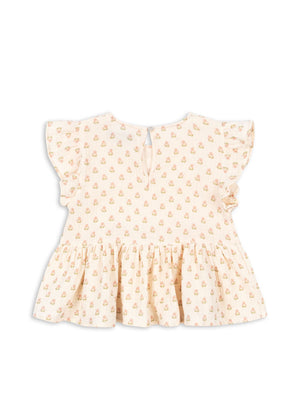 The Konges Slojd Baby Girls’ and Girls’ Coco Top is a light cream blouse featuring a charming small floral print, flutter sleeves, a ruffled peplum silhouette hem, and a back button keyhole closure, displayed flat on a white background.