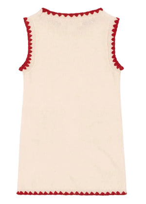 The Girls' Collette Dress by Konges Slojd is a sleeveless cream knitted wool dress with a fitted silhouette and red scalloped trim on the neckline, armholes, and hem, shown laid flat and photographed from the back.