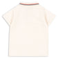 Back view of the Konges Slojd Baby Boys’ and Boys’ Florian Polo Shirt, a cream short-sleeve style with a regular collar and button placket, featuring ribbed edging decorated with red, navy, and white stripes.