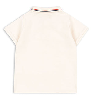 Back view of the Konges Slojd Baby Boys’ and Boys’ Florian Polo Shirt, a cream short-sleeve style with a regular collar and button placket, featuring ribbed edging decorated with red, navy, and white stripes.