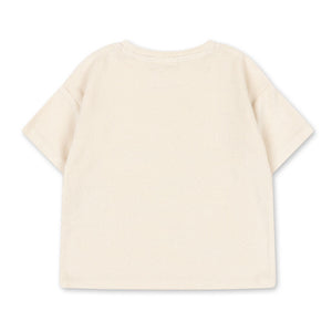 The Konges Slojd Baby Boys’ Itty Tee, a short-sleeved off-white t-shirt crafted from organic cotton terry, is displayed laid flat with the back facing up against a white background.