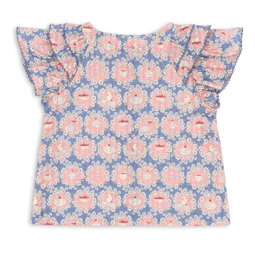 Back view of the Konges Slojd Baby Girls’ and Girls’ Kim Frill Shirt, a short-sleeved top featuring blue and pink floral and teacup patterns with frill detailing on the ruffled sleeves.
