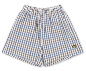 Baby boys’ and boys’ Kim Short by Konges Slojd, featuring a blue and white checkered design, crafted from breathable organic cotton with an elastic waistband and a small yellow embroidered detail on the lower right leg, laid flat on a white background.