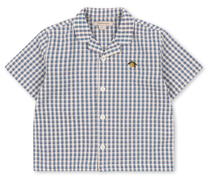 The Konges Slojd Baby Boys’ and Boys’ Kim Short Sleeve Shirt features a charming blue and white check seersucker pattern, crafted from soft organic cotton, and is finished with a small embroidered bee on the left chest.