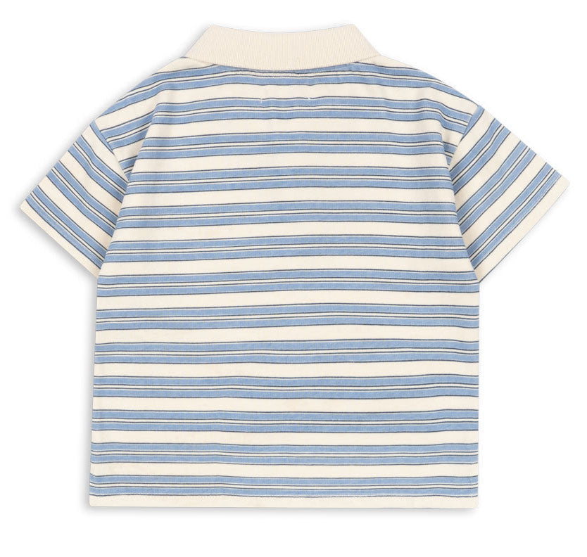 The Boy’s Spotty Short Sleeve Polo by Konges Slojd features a relaxed fit with short sleeves and blue and beige horizontal stripes, shown from the back against a white background.