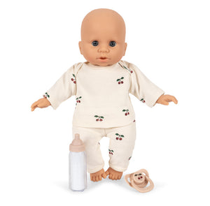 The Baby Doll Nursery Suitcase by Konges Slojd features a soft bald doll in cherry pajamas with nursery accessories, perfect for imaginative play.