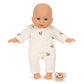 A Poppy Doll Stroller Set doll wearing a cream-colored long-sleeve shirt and cherry-patterned pants, with a matching pacifier on the floor nearby.