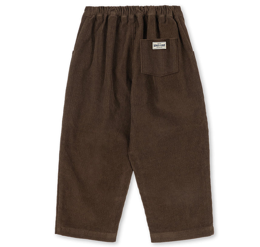 Dark brown relaxed fit Konges Slojd Baby Boys’ and Boys’ Remy Pants with an elastic waistband and a single back pocket featuring a rectangular brand label.