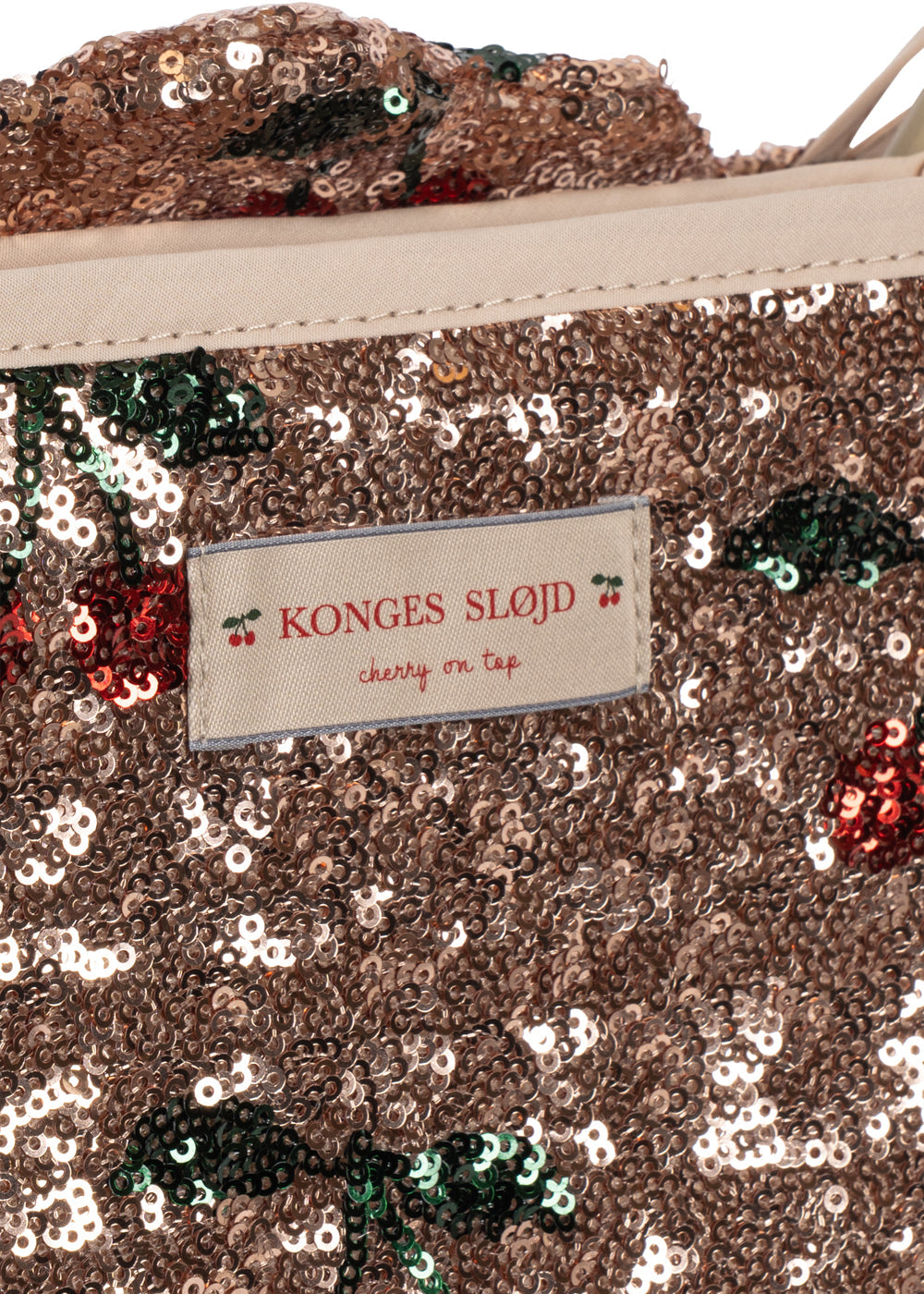 A close-up of the Konges Slojd Sparkly Doll Stroller with a label and small cherry illustrations.