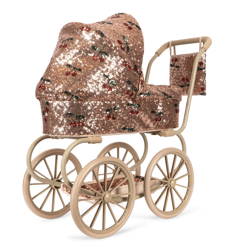 Konges Slojd Sparkly Minnie Doll Pram with a foldable sun canopy, covered in sparkly bronze sequins with a cherry pattern and featuring four spoked wheels.