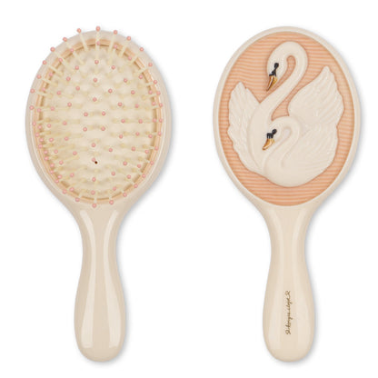 The Konges Slojd Swan Beauty Set features two beige hairbrushes—one with pink-tipped bristles, one with swan details—ideal for pairing with a hand mirror.