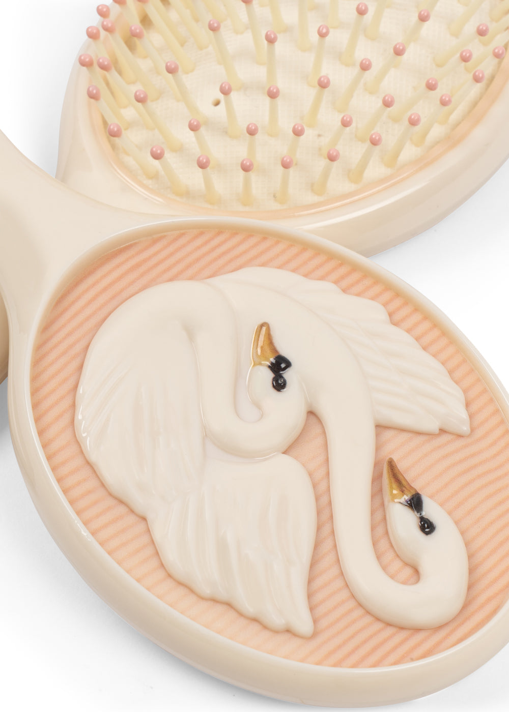 A close-up of the Swan Beauty Set by Konges Slojd, showing a hairbrush adorned with two white swans with black and orange beaks.