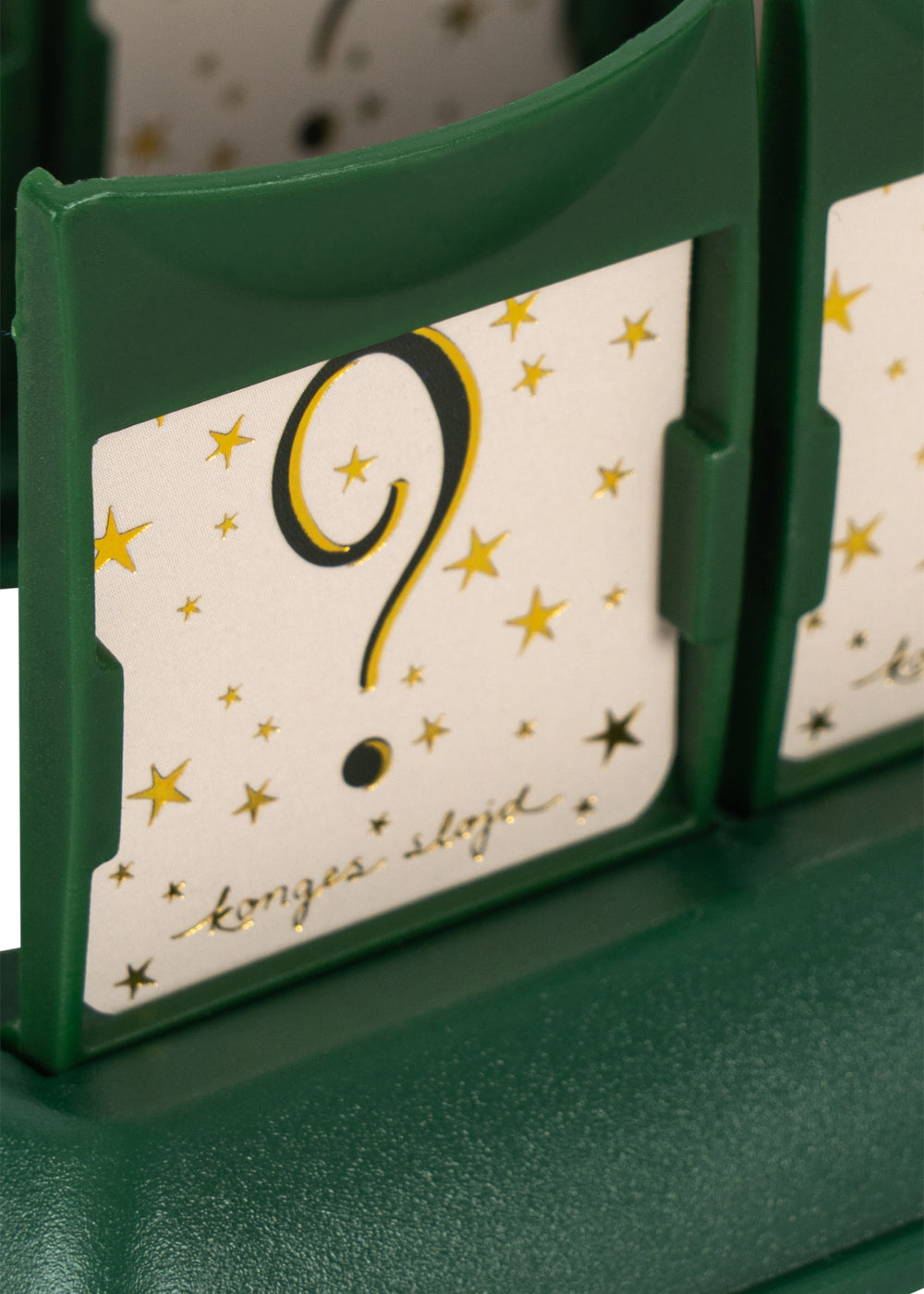 A green game piece holds a card with a bold question mark, surrounded by gold stars and cursive script. Who Am I Game by Konges Slojd is perfect for family guessing fun!.