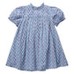 The Girls’ Lucia Dress by Pink Chicken is a light blue short-sleeve dress with a ruffled collar, adorned with a small red and green floral print and detailed delicate navy smocking at the chest and sleeves for added charm.