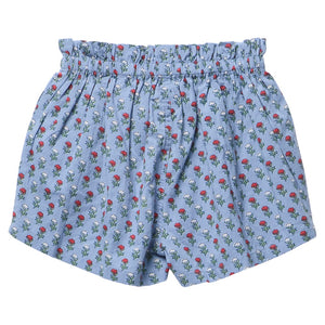 Girls’ Theodore Short by Pink Chicken in light blue, featuring a ruffled elastic waistband and decorated with a charming pattern of small red and green blockprint floral designs.