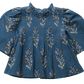 Pink Chicken Girls’ Jaipur Top features a floral pattern, pleated front, bell sleeves, ruffled collar, and navy glitter buttons for sparkle.