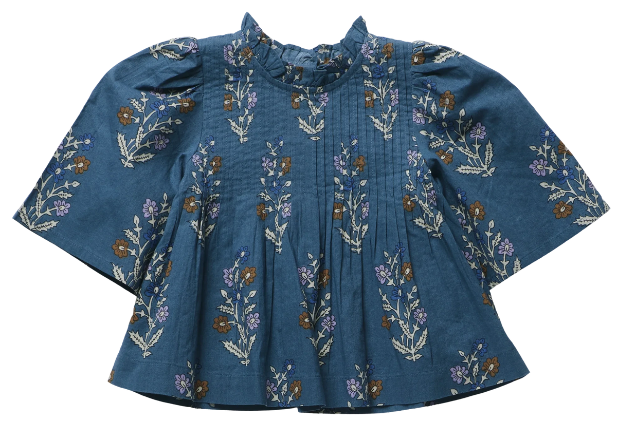 Pink Chicken Girls’ Jaipur Top features a floral pattern, pleated front, bell sleeves, ruffled collar, and navy glitter buttons for sparkle.