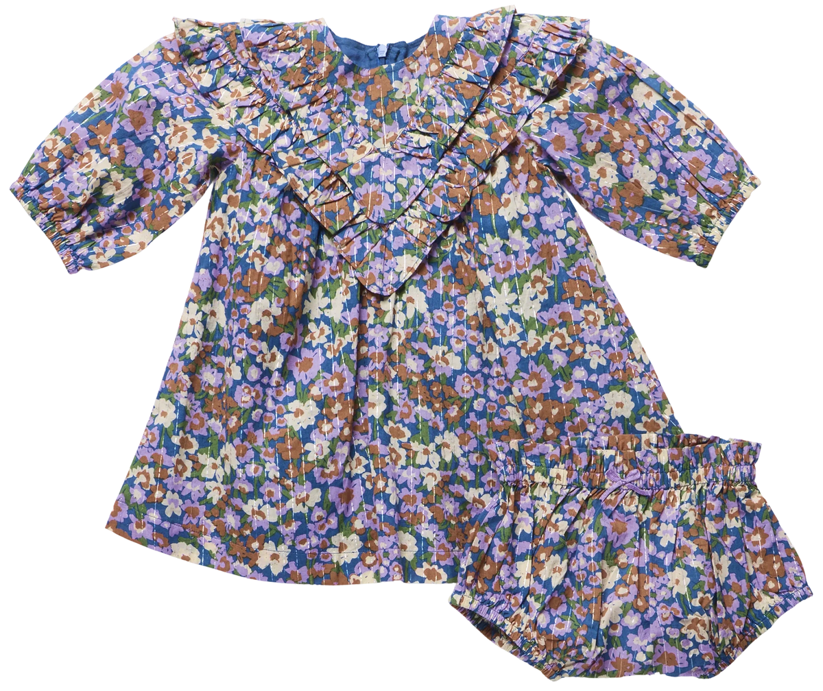 The Baby Girls’ Everly Dress Set by Pink Chicken features a long sleeve floral dress with ruffle collar and matching bloomers in purple, blue, green, and tan prints.