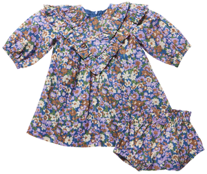 The Baby Girls’ Everly Dress Set by Pink Chicken features a long sleeve floral dress with ruffle collar and matching bloomers in purple, blue, green, and tan prints.