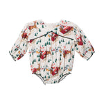 Pink Chicken Baby Girls’ Wynne Bubble long-sleeved holiday romper featuring a Santa sleigh print with reindeer, pine trees, and small houses, finished with dark green trim.