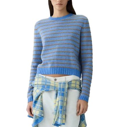 A woman wears the Guest in Residence Pebble Stripe Shrunken Crew, a blue and gray striped cashmere sweater, with a yellow and blue plaid shirt tied around her waist and white pants.