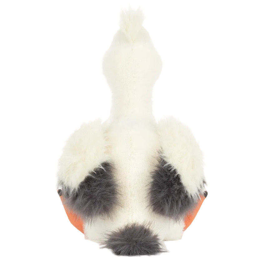 Jellycat’s Keli Pelican stuffed animal features fluffy white wings, gray accents, orange feet, and a tufted tail—just like seen on The Beak talk show—shown here from the back.