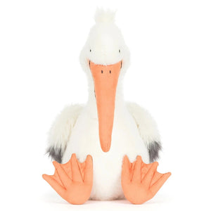 Jellycat's Keli Pelican plush toy, featuring white fur, an orange beak and feet, and gray wingtips, sits upright against a plain background—ready to host the next episode of "The Beak" talk show.