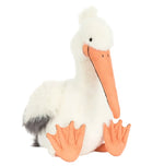 Jellycat’s Keli Pelican plush toy features white fur, an orange beak and webbed feet, a gray tail accent, and sits upright—adorable and inspired by the character from The Beak talk show.