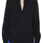 A person wears the Callas Milano Olympia Top, a black long-sleeved blouse with a collarless neckline, paired with blue pants and shown from the waist up.