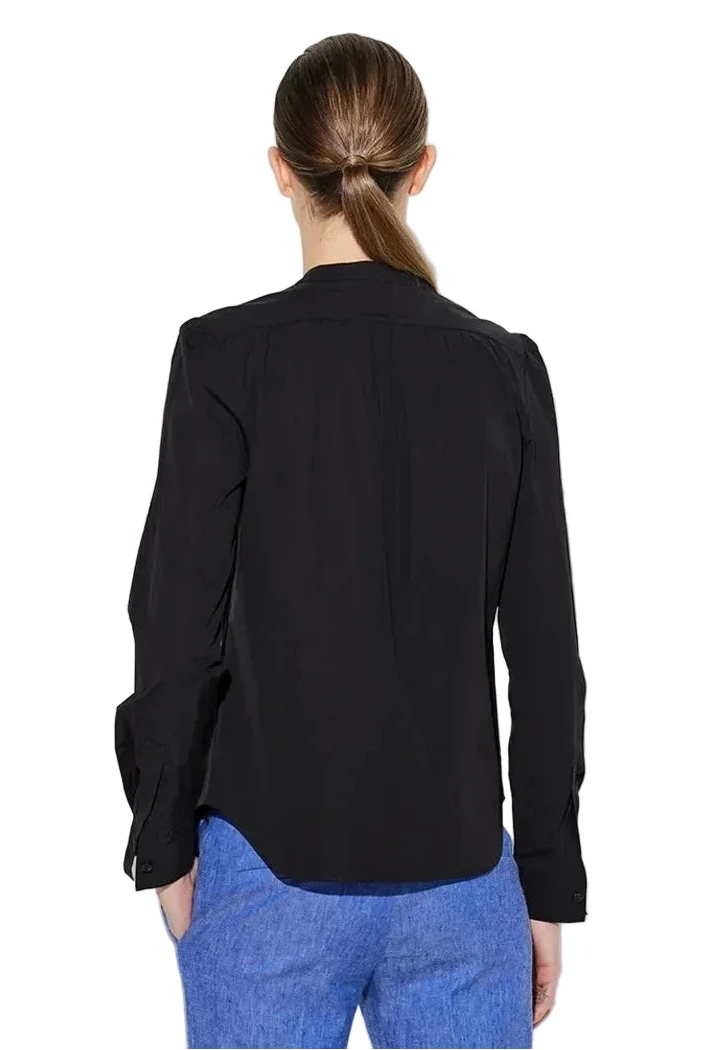 A woman with brown hair in a low ponytail is shown from the back against a white background, wearing the Callas Milano Olympia Top in black with blue pants.