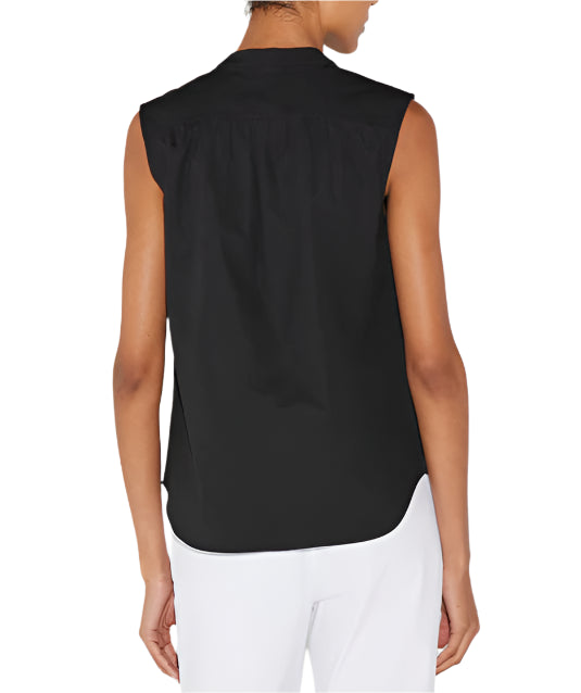 A person exudes modernist style, donned in a sleeveless Olympia top by Callas Milano and white cotton poplin pants, viewed from the back.