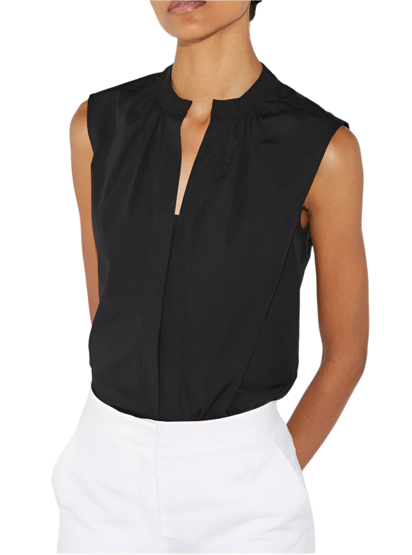 A person wearing the Olympia Sleeveless Top by Callas Milano paired with white cotton poplin pants, standing against a white background.
