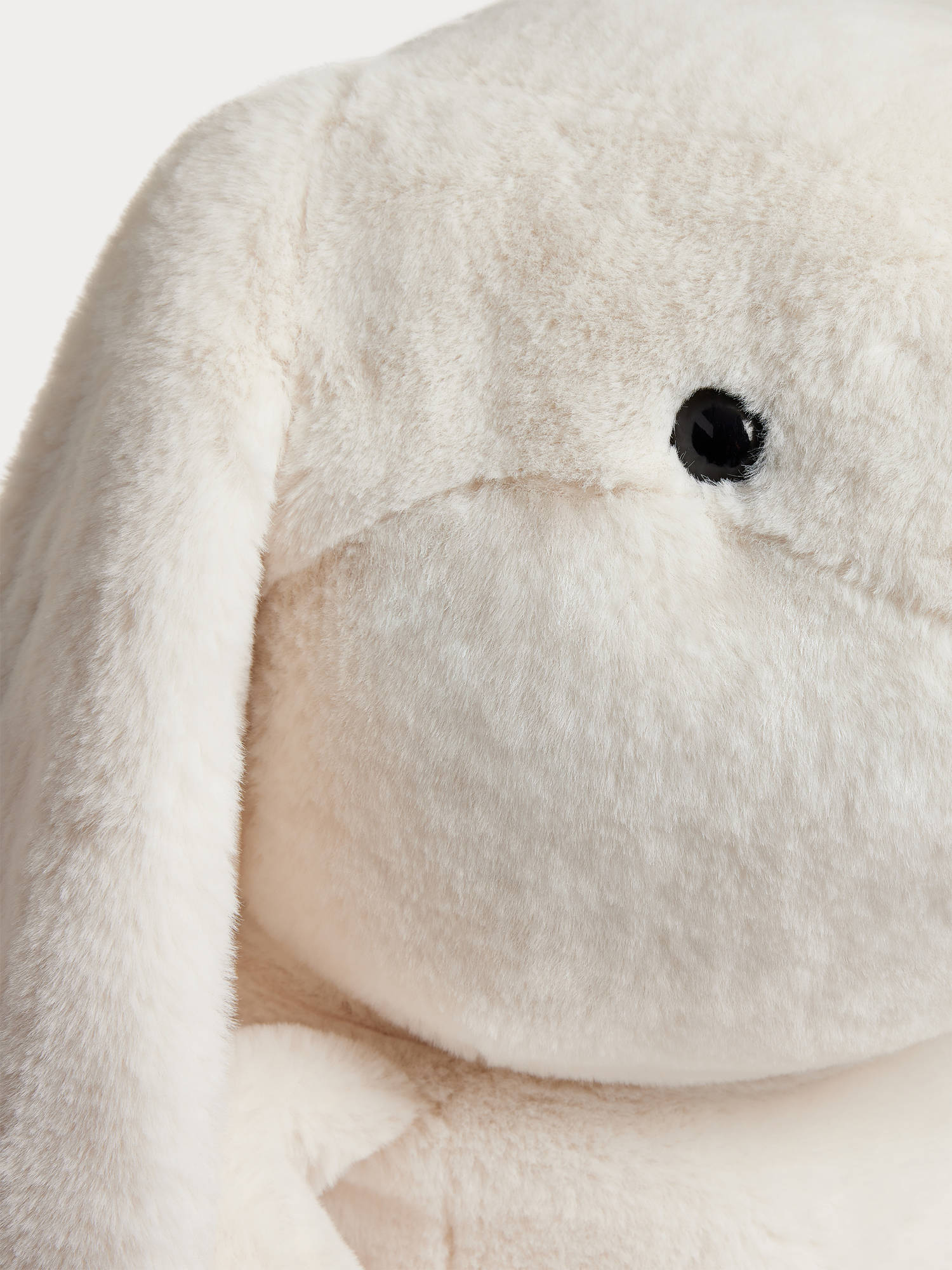 Close-up of the XXL Signature Rabbit by Bonpoint, an extra-large plush stuffed animal featuring cream-colored fur, a black plastic eye, and a floppy ear—this cuddly toy embodies the charm of the iconic Bonpoint bunny.
