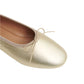 Close-up of Mansur Gavriel's Dream Ballerina, a gold flat made from Italian lambskin leather, featuring a knotted bow on the front and a rounded toe.